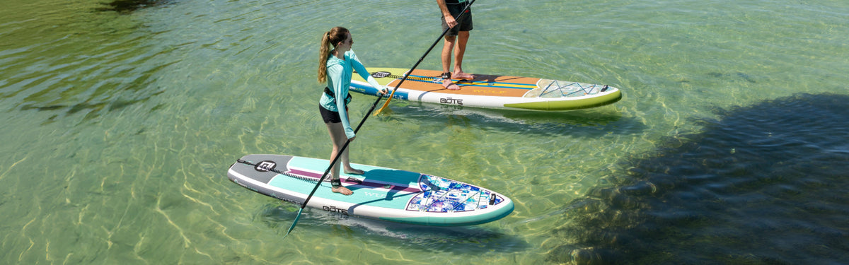Two people paddleboarding on a clear body of water.