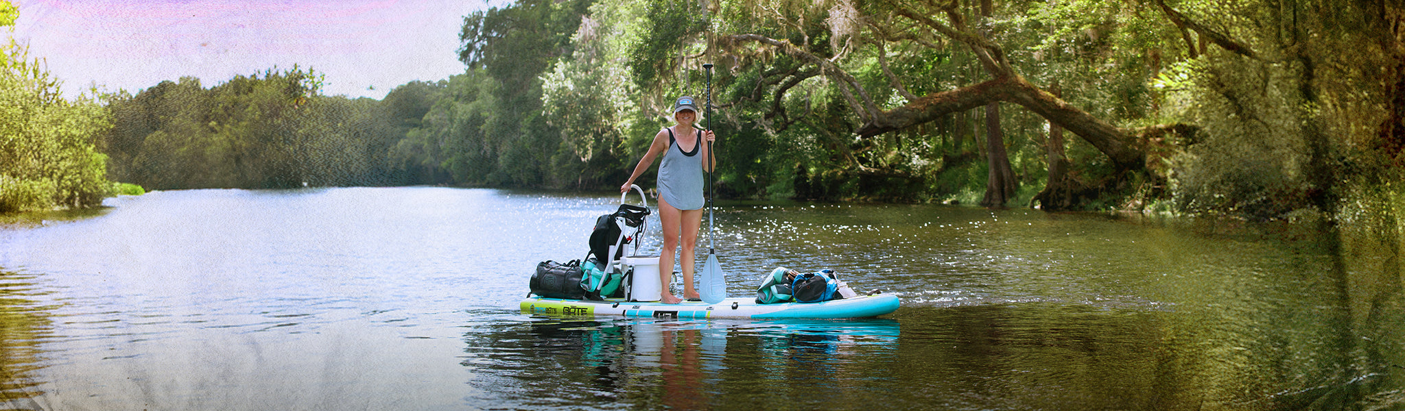Person on a stand-up paddleboard in a river surrounded by trees