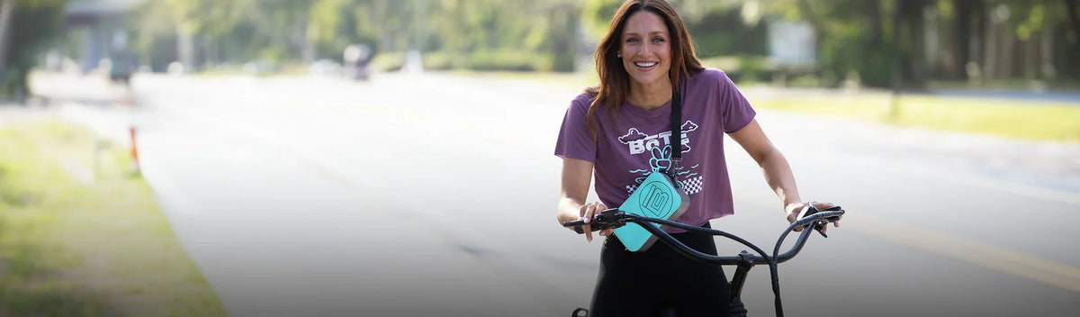 Woman riding a bicycle on a road with trees and blurred background