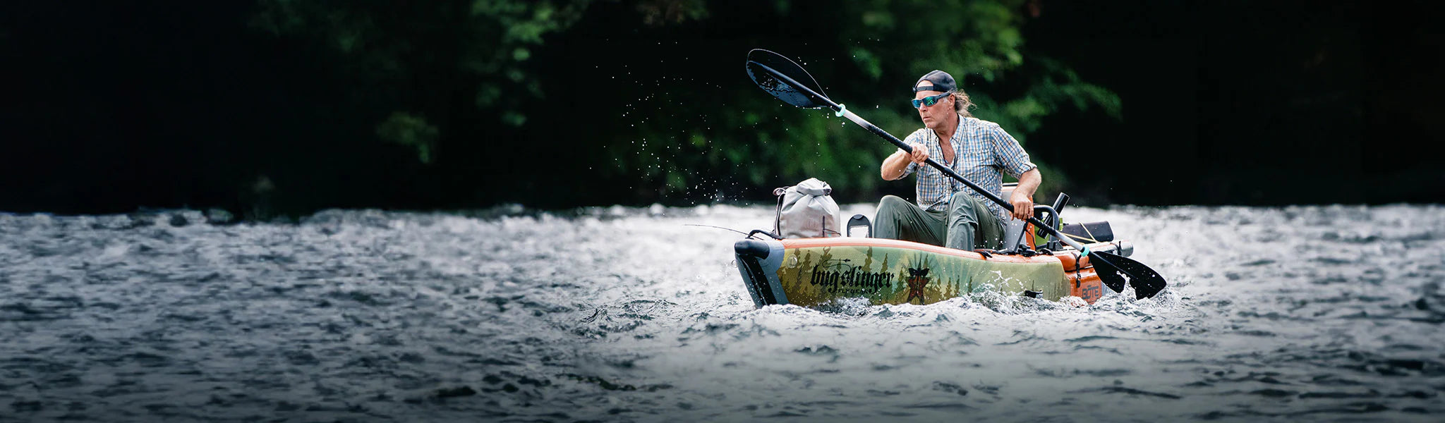 Man kayaking through gentle river rapids surrounded by dark forest backdrop.