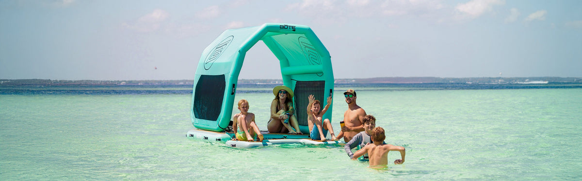 People sitting on a Hangout Dock under a teal canopy in clear calm water.