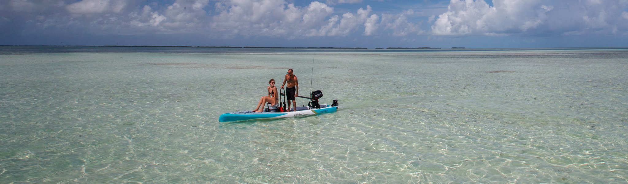 Man and woman on motorized skiff floating in clear turquoise water.