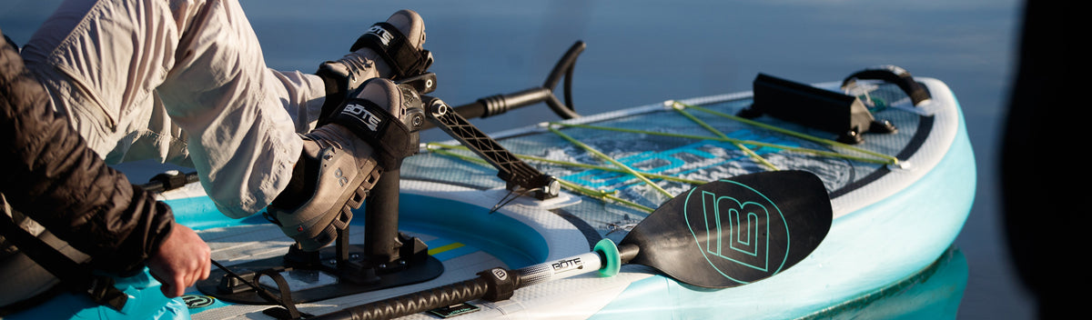 Close-up of feet pedaling on blue paddle board with paddle resting beside.
