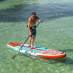 A man stand up paddle boards on the EasyRider Aero in shallow water.