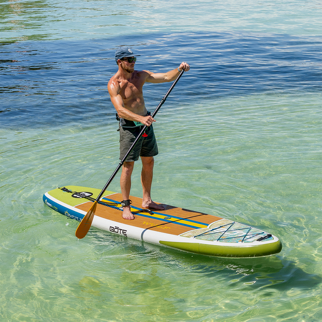 Person paddling the WULF Aero across clear shallow water on a sunny day.