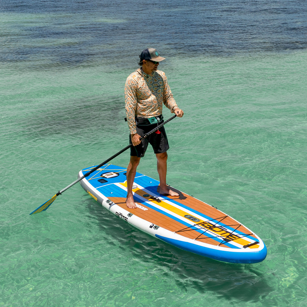 Man stand-up paddleboarding on a LowRider Aero Tandem in clear water.