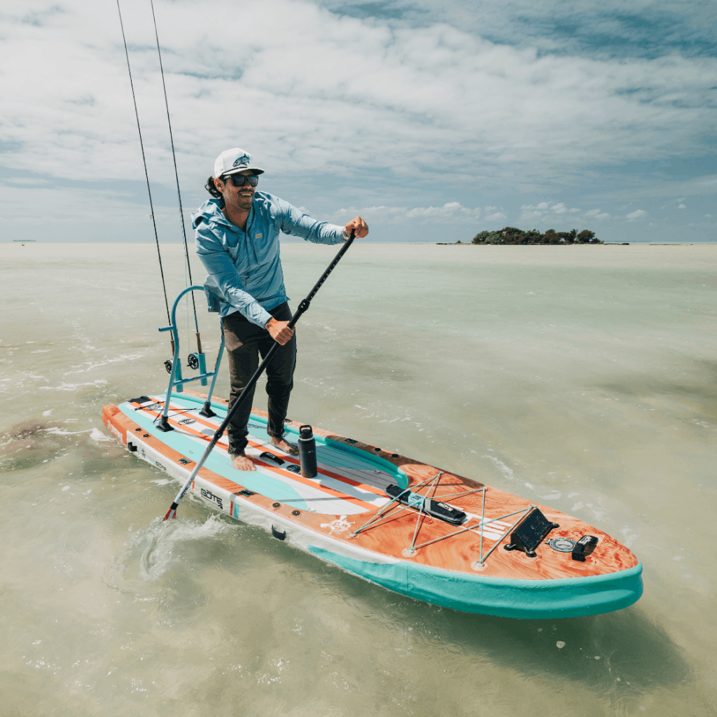 Angled view of Rackham Aero paddle board with fishing gear on shallow water.