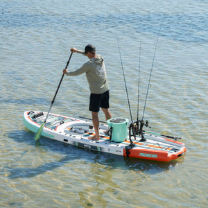 Angled view of ProRider Aero paddle board with fishing rods and cooler on clear water.