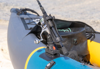 Close-up of a fishing rod holder mounted to a universal mount point on the bow of a teal and gray BOTE Argo inflatable kayak.