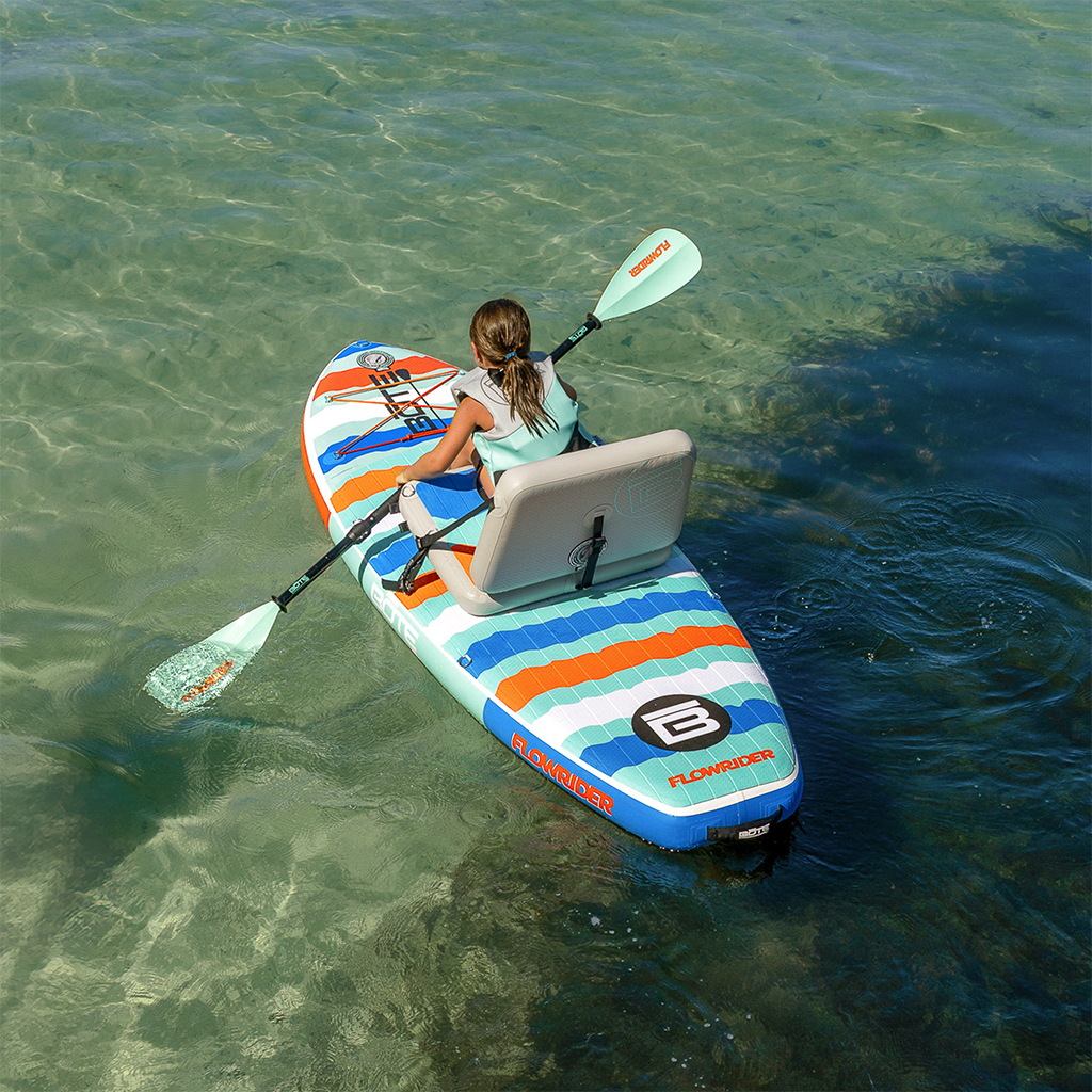 Aerial view of child seated kayaking on a Kids FlowRider Aero in clear water.