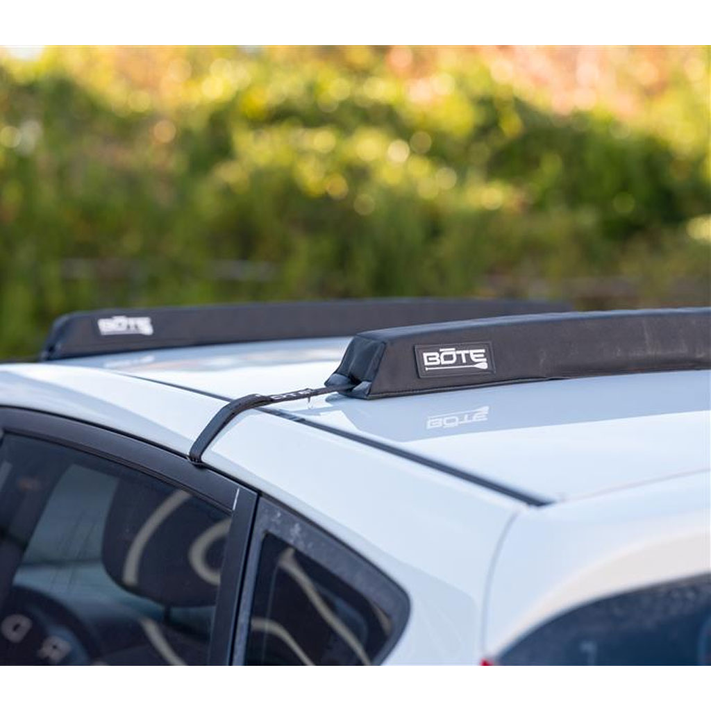 Car roof rack with BOTE logo on a white vehicle in an outdoor setting so you can protect your board and car while driving.