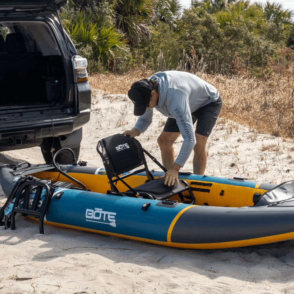 Angled view of Solis Seat attached to an inflatable kayak on a sandy shore.