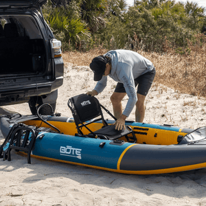 Angled view of Solis Seat attached to an inflatable kayak on a sandy shore.