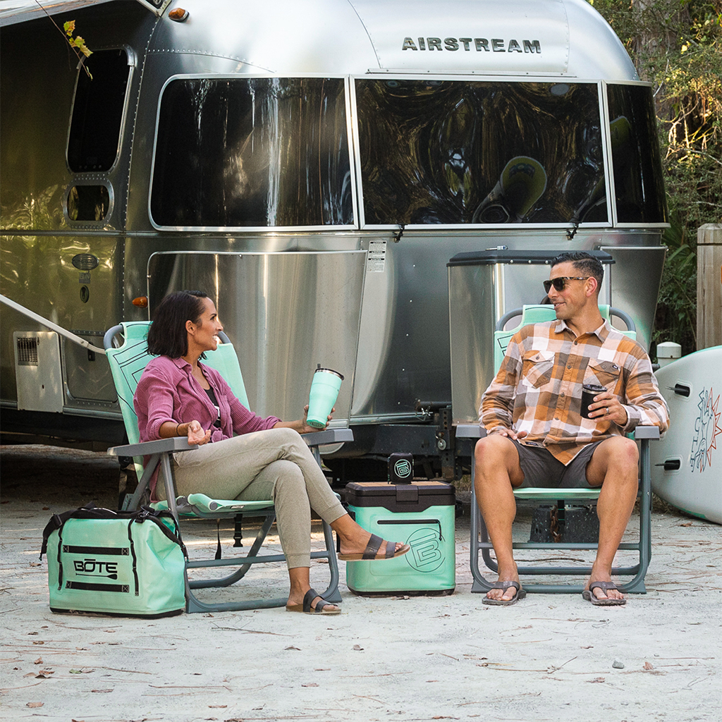 Mule Outpost Chair set with cooler and gear beside camper trailer outdoors.