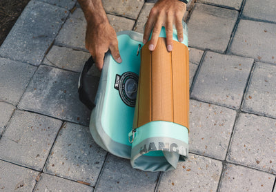 Close-up of hands rolling up inflatable lounge for compact storage.