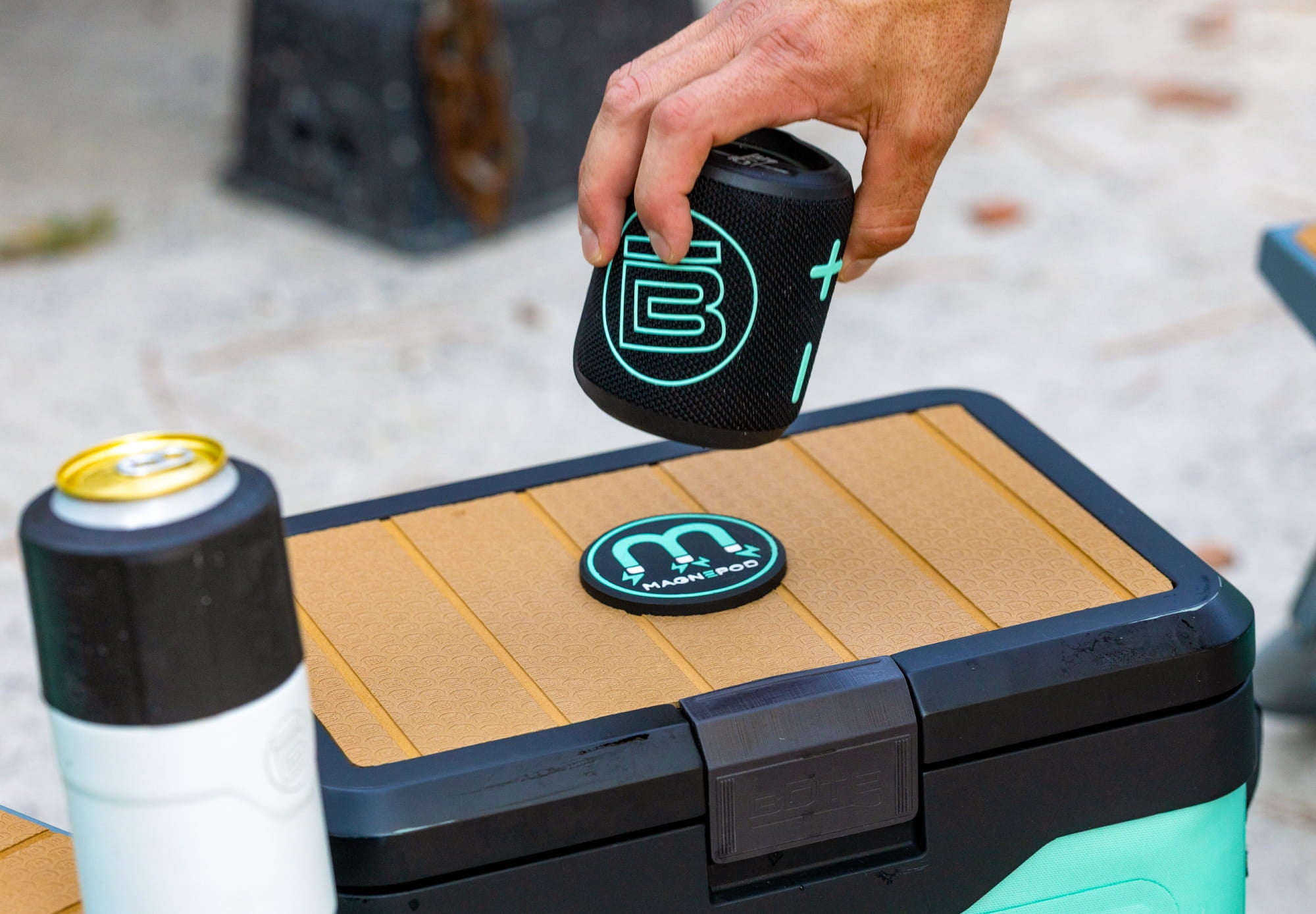 Hand placing speaker onto magnetic dock on KULA Mule cooler lid.
