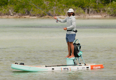 Side view of Rackham Aero paddle board with fishing setup in shallow water.