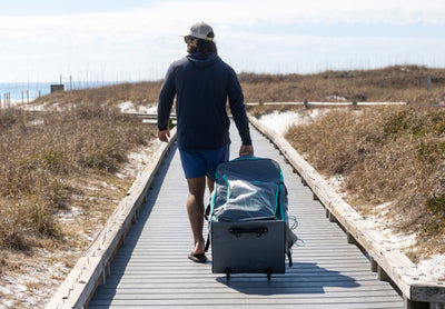 Rear view of Rackham Aero travel bag being rolled down a beach boardwalk.