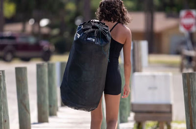 Woman carrying packed Hangout Ladder in a black storage bag.