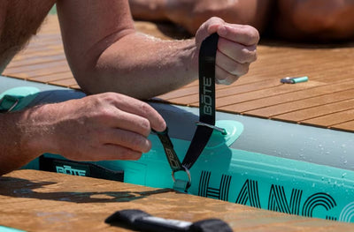 Close-up of hands attaching strap to Hangout Ladder on deck surface.