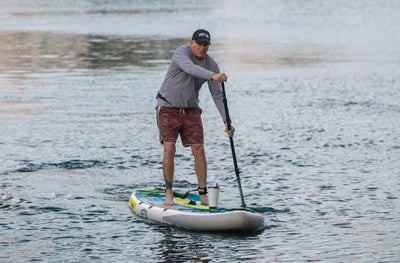 Man paddling the LowRider Aero Tandem solo on calm water.