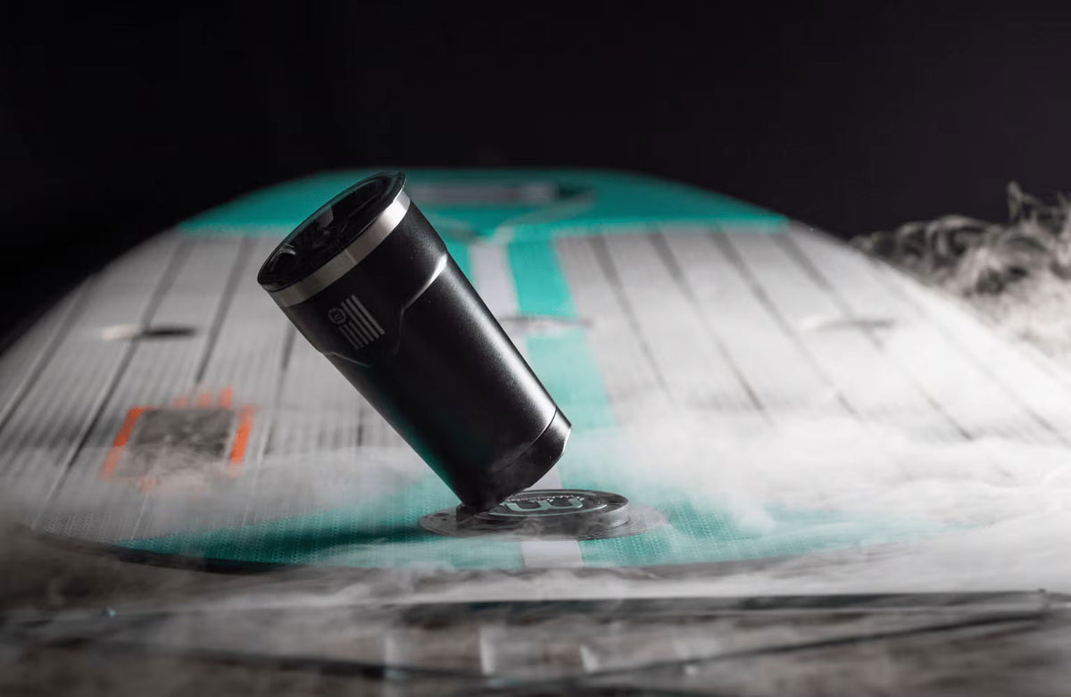 Angled view of black MAGNEPOD tumbler attached to a paddle board in mist.