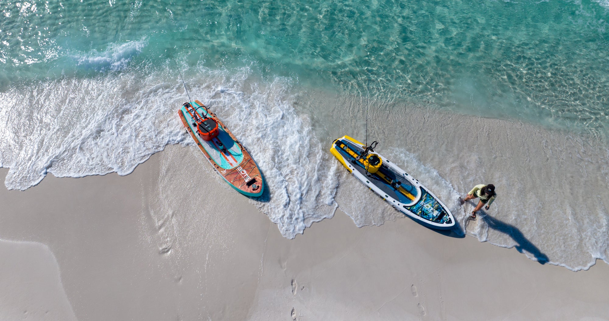 Top view of Rackham Aero paddle boards on a sandy beach with clear water.