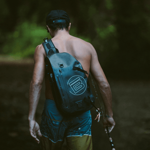 Man carrying his fishing rods in hand with the black Highwater Slingpack on his back