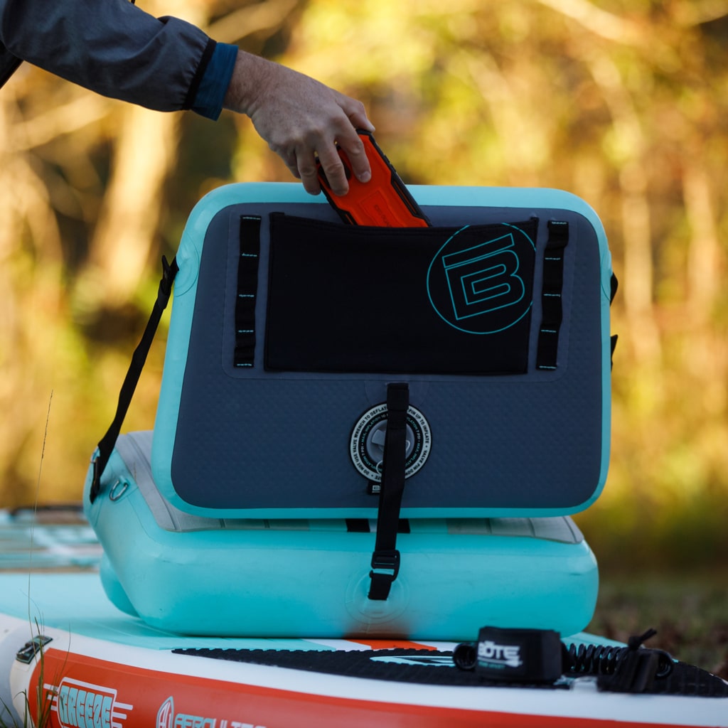 Man placing his cell phone into the stretch pocket on the back of the Aero SUP Paddle Seat