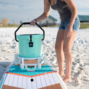 Woman putting her KULA 5 cooler into her white Bucket Rac that is on her Flood paddle board