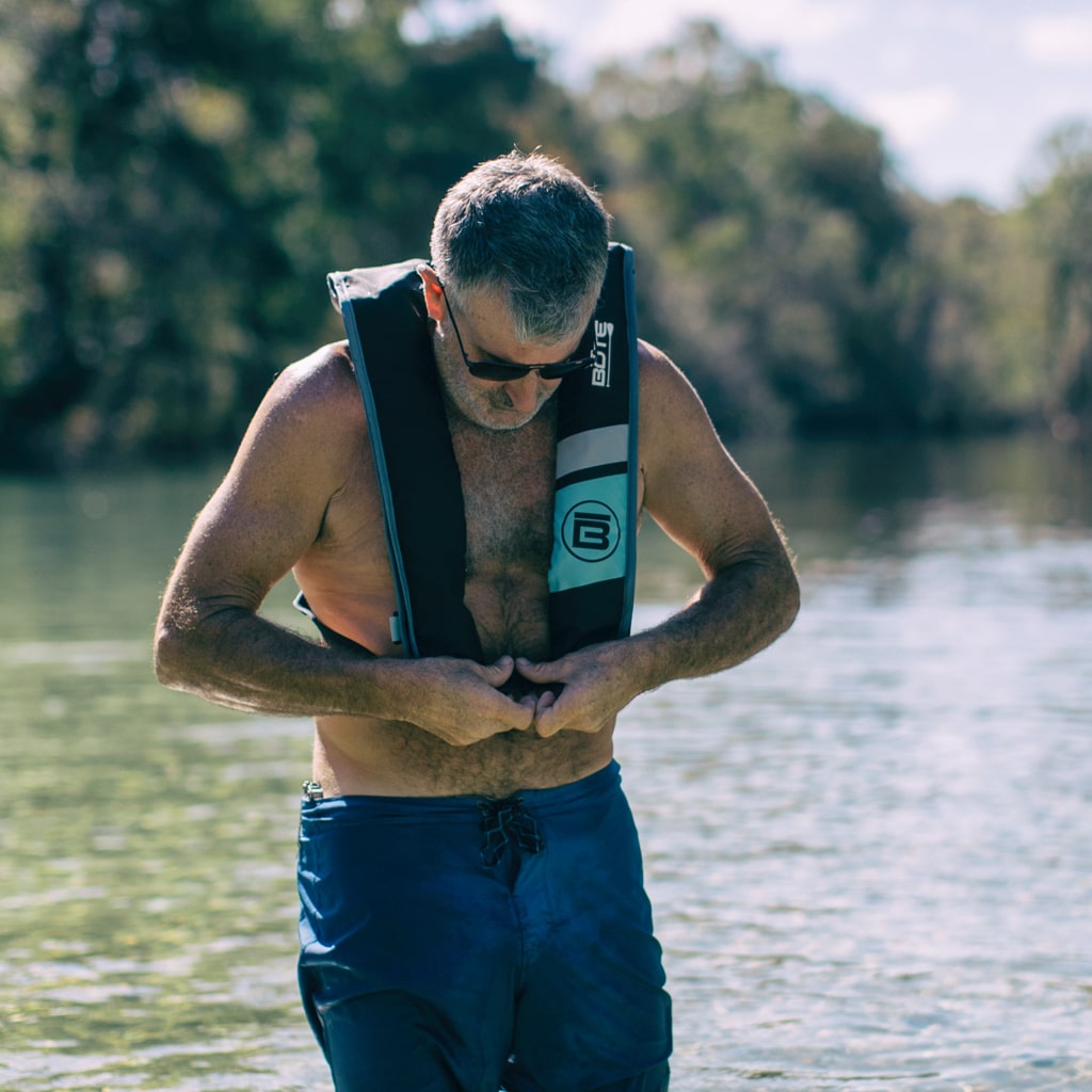 Man clasping the waist buckle of the BOTE Inflatable Vest PFD around his waist