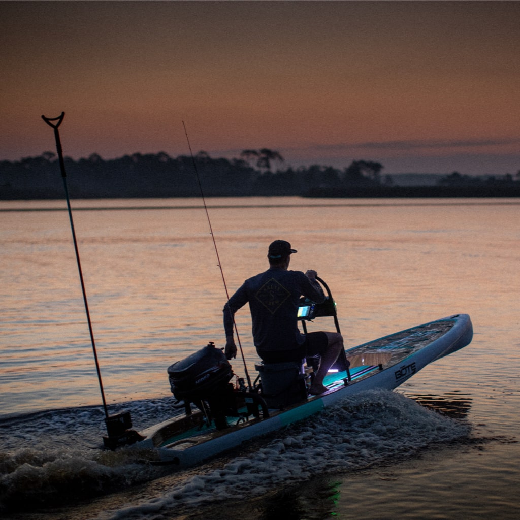 Man steering paddle board at dusk using mounted Power Rac with lit control panel.