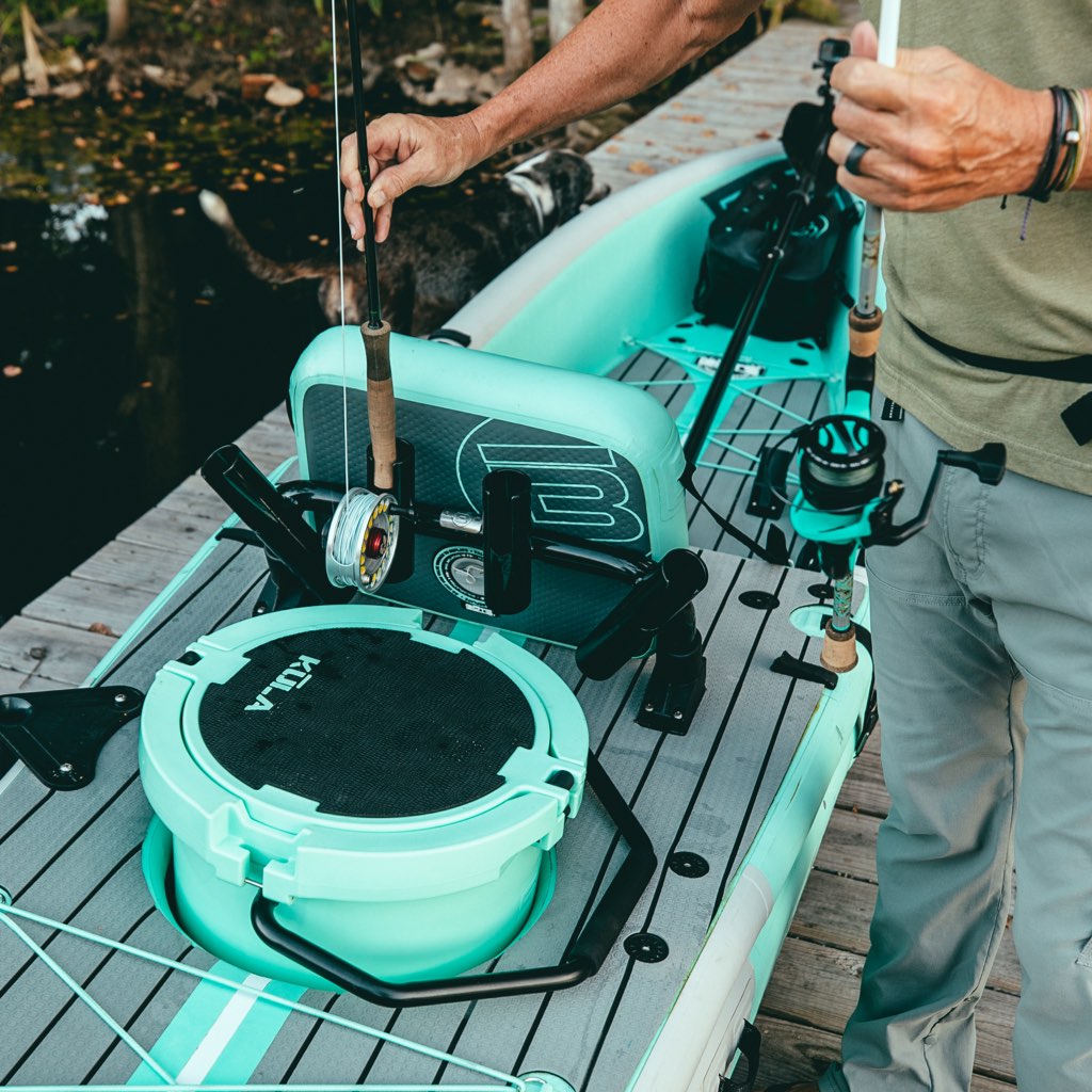 Man placing fishing rods into Rocket Rac Black mounted behind KULA cooler.