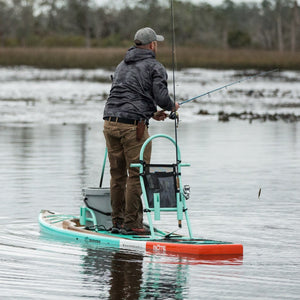 Lifestyle image of Tackle Rac Seafoam on paddle board while man stands and fishes.