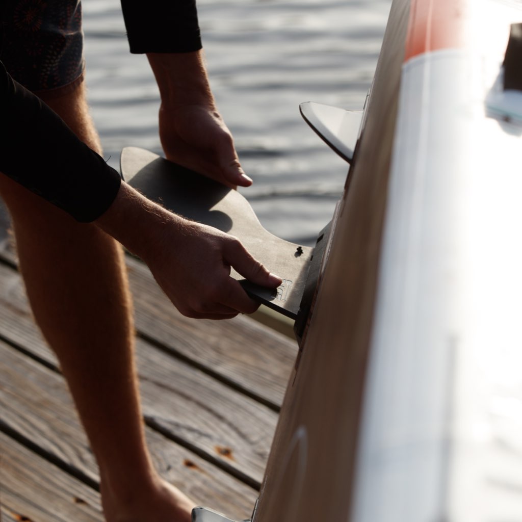 Man installing fin onto paddle board